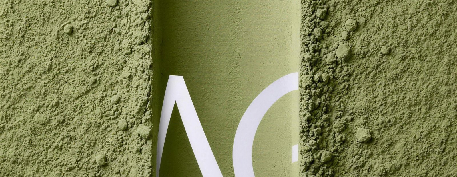 A green canister half-buried in matcha powder